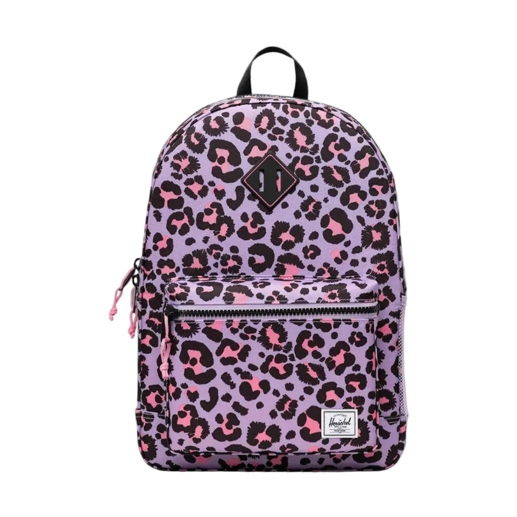 A Herschel backpack in a lavender purple leopard print pattern with black and pink spots, shown against a dark gray gradient studio background.