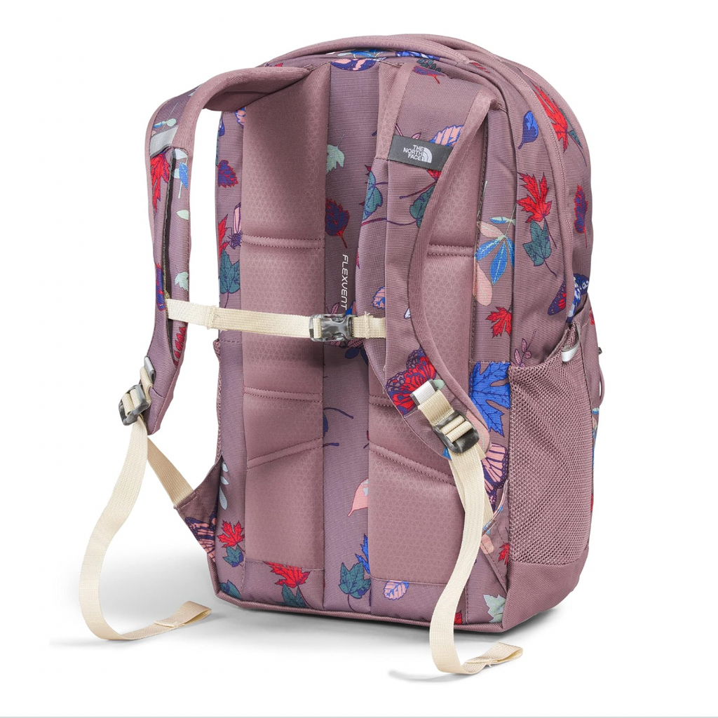 The North Face backpack shown from the back, featuring a dusty mauve base color with a colorful floral print in red, blue, and green. It has padded back panels, adjustable shoulder straps, a compression strap, and a side mesh pocket, photographed on a clean white background.