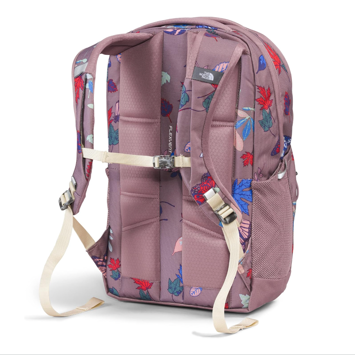 The North Face backpack shown from the back, featuring a dusty mauve base color with a colorful floral print in red, blue, and green. It has padded back panels, adjustable shoulder straps, a compression strap, and a side mesh pocket, photographed on a clean white background.