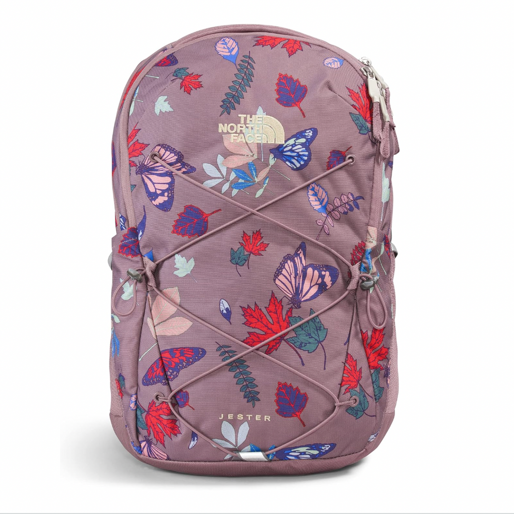 A The North Face Jester backpack in a dusty mauve color, decorated with a vibrant multicolor print of butterflies, leaves, and maple leaves, featuring lace-up front details and a gold-tone logo.