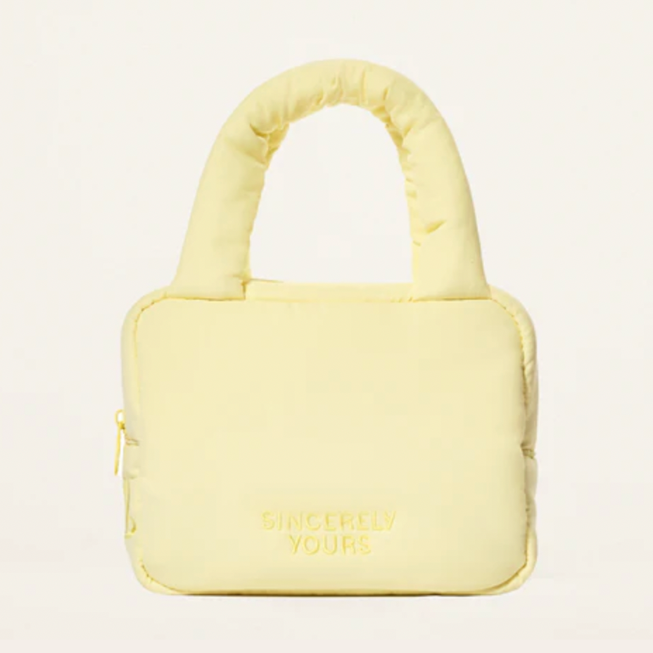 A pale yellow puffer-style handbag with a padded top handle and embossed 'SINCERELY YOURS' branding on the front, shown against a plain white background.
