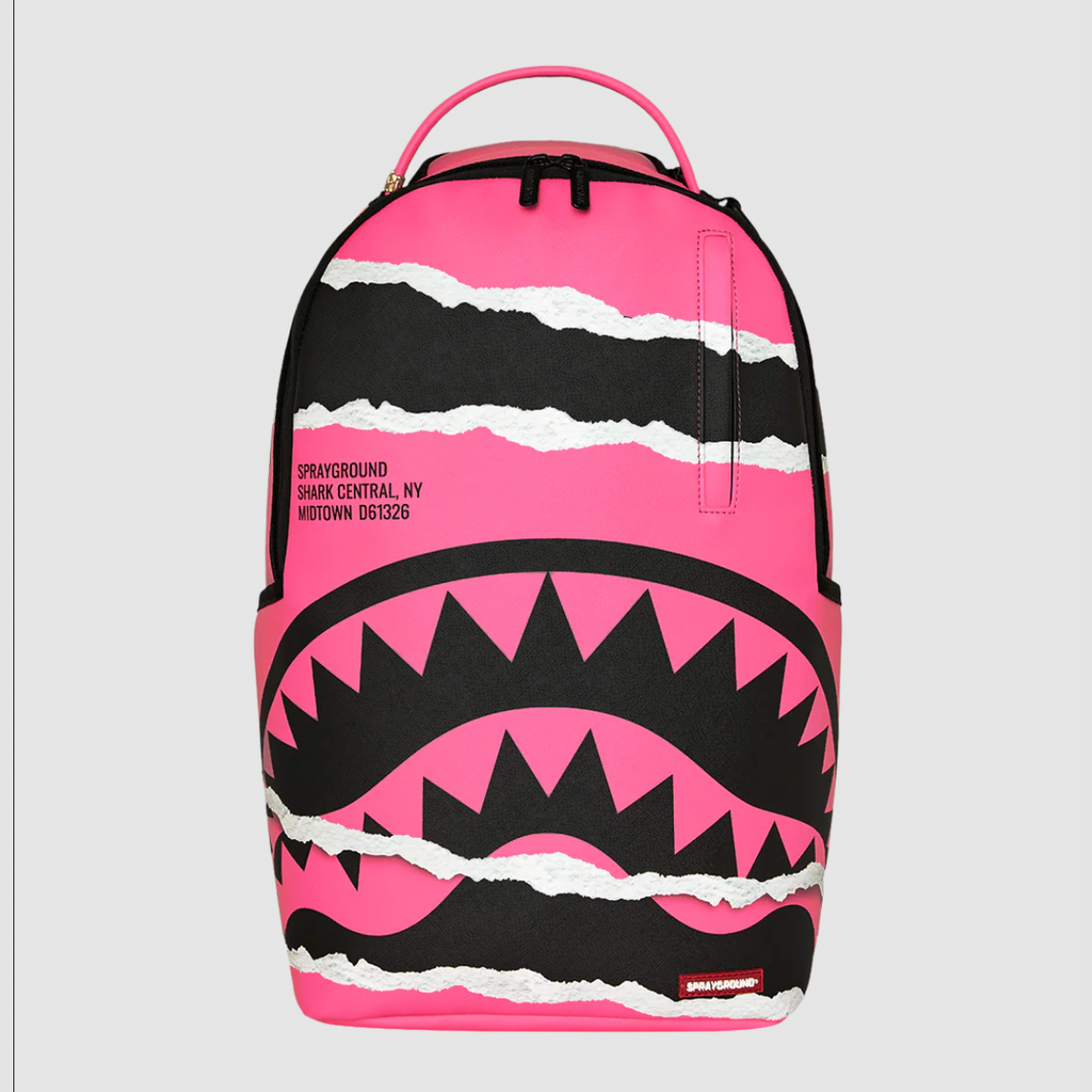 A Sprayground Shark backpack in vibrant pink and black, featuring a shark mouth graphic with white torn-paper accents, shown against a light gray background.