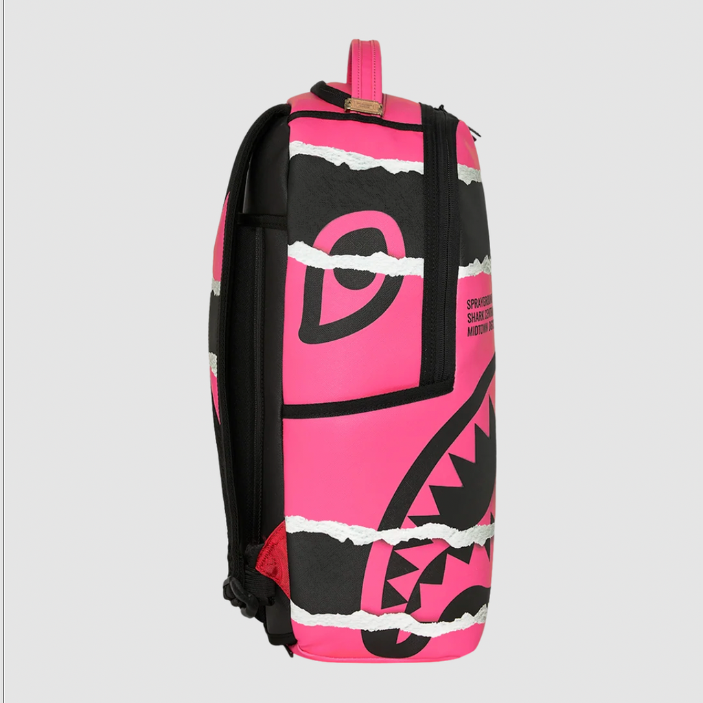 A backpack featuring a bold pink and black graphic design with torn-paper style white accents, shown against a neutral light gray background.