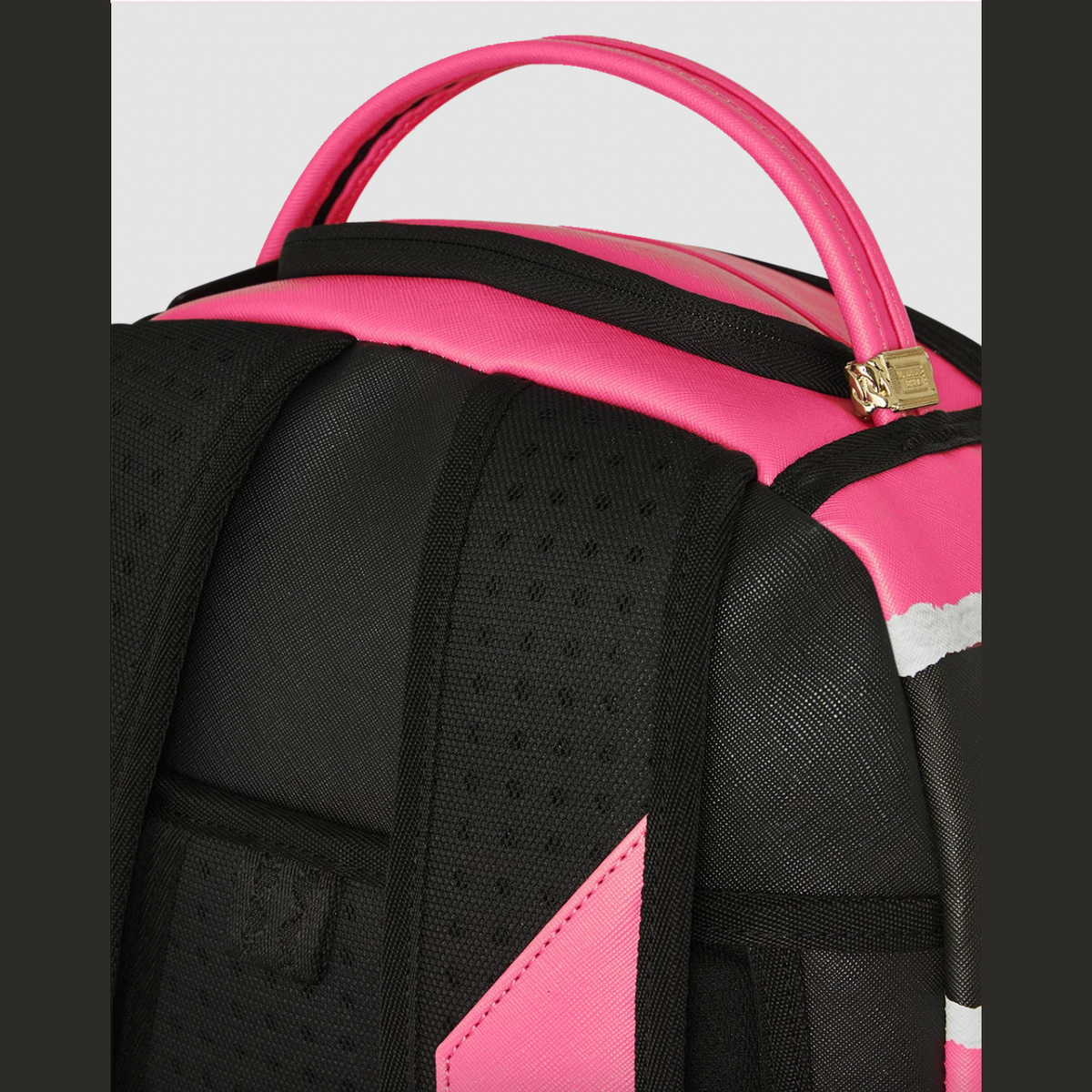 Close-up of a black and hot pink backpack showing the top handle, zipper with a gold-tone lock, textured fabric panels, and side pocket details.